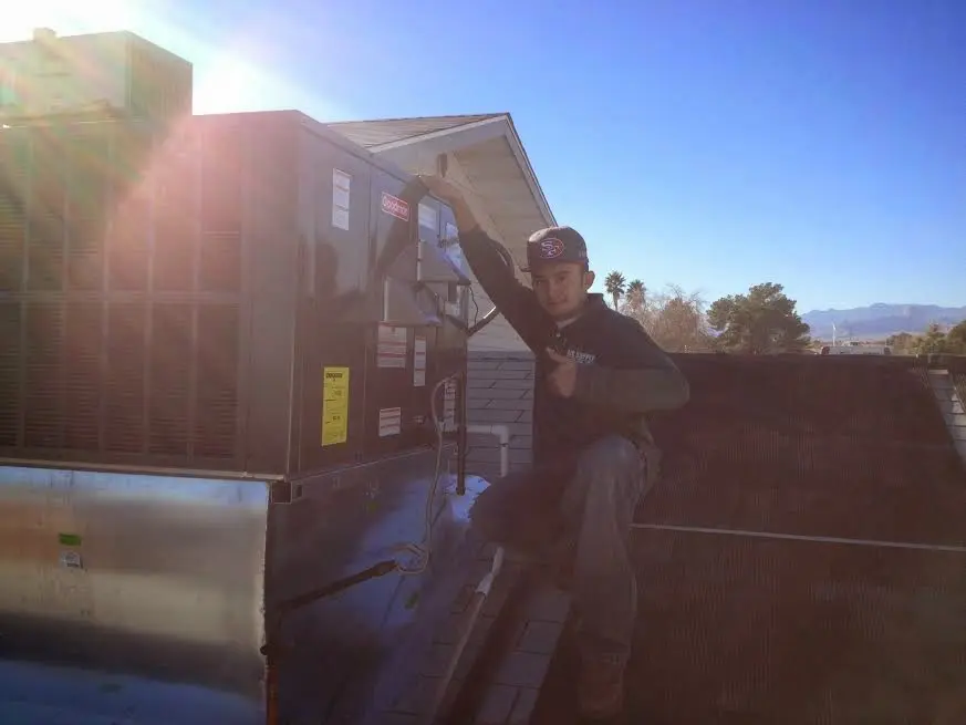 HVAC technician performing AC Tune-Up on a rooftop unit in Rockton